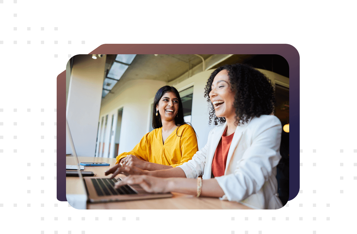 two female colleagues using a laptop smiling and laughing