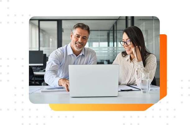 A male and female colleague discussing business in front of a computer