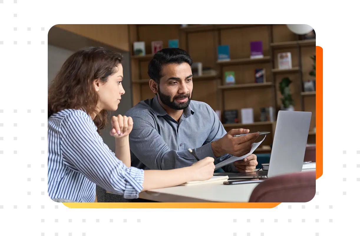 A male and female colleague reviewing a project on their computer in a technology company