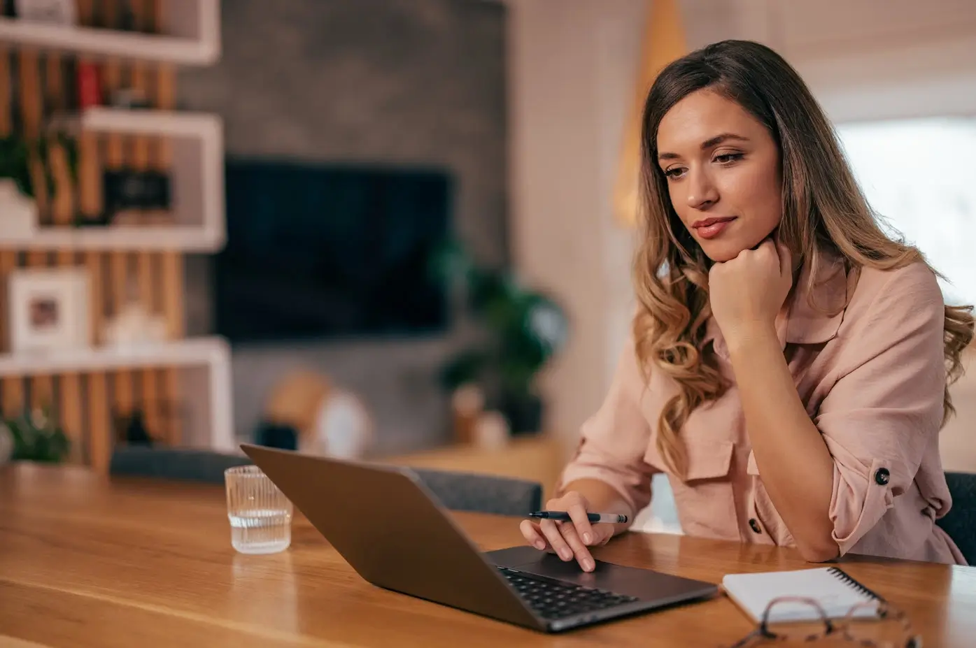 A female sitting at a table viewing content on her laptop